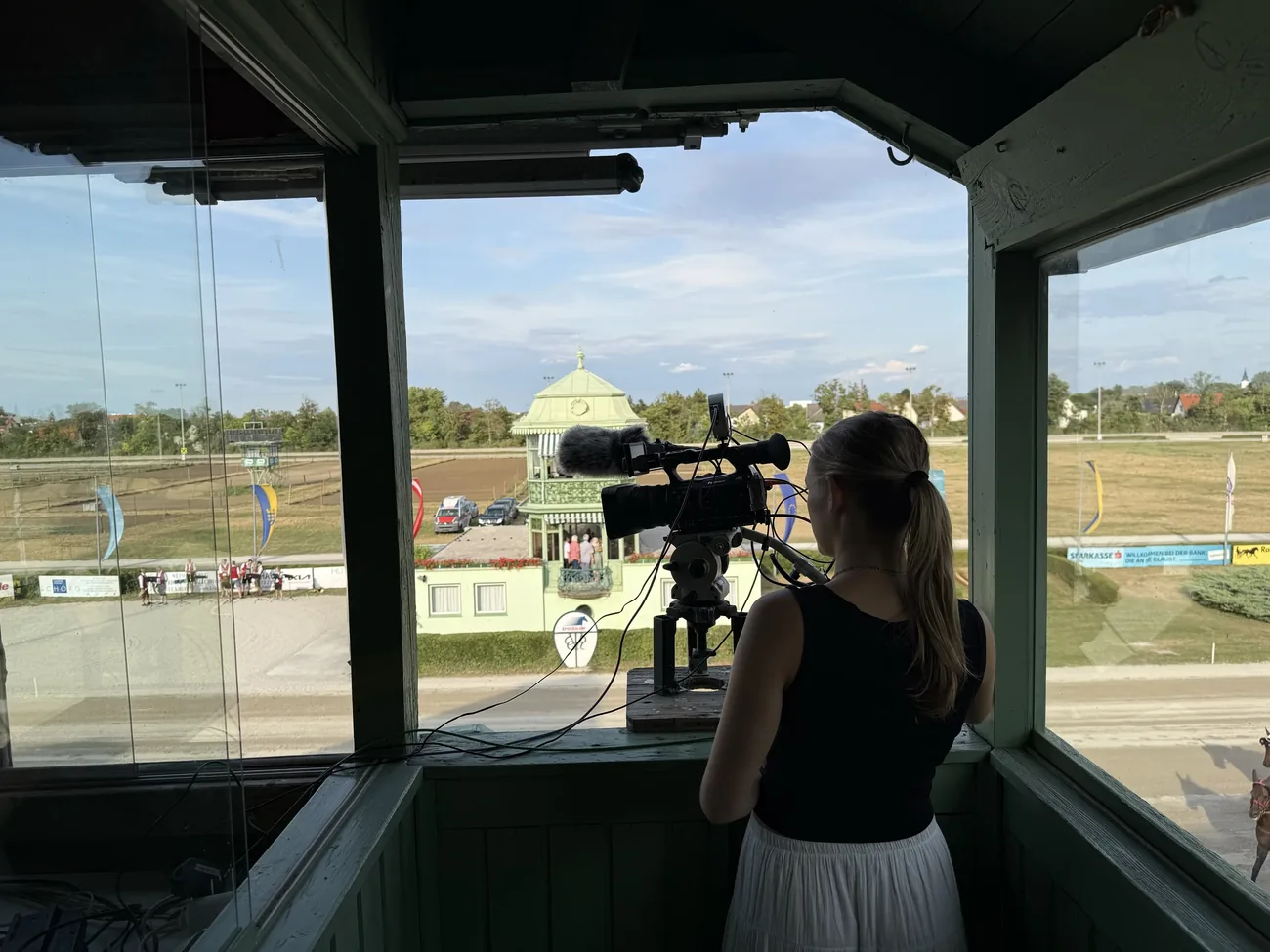 Photo-finish camera operator looking over the Baden harness racing track from a trackside window.